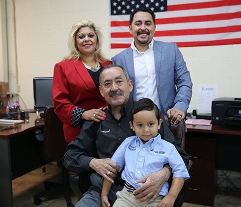 A family posing for a photo in an office with an american flag.