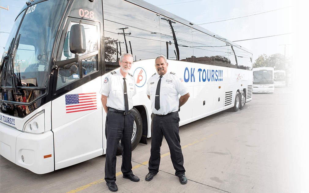 Two men standing in front of a white bus.