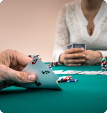 A woman is holding cards at a poker table.
