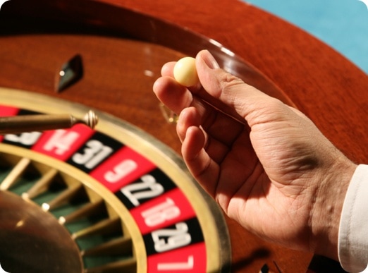 A hand is holding a ball on a roule wheel.