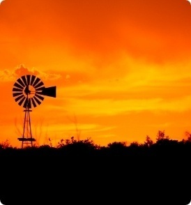 An orange sunset with a windmill in the background.