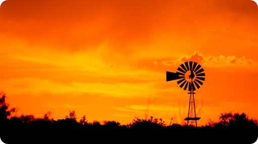 An orange sunset with a windmill in the background.