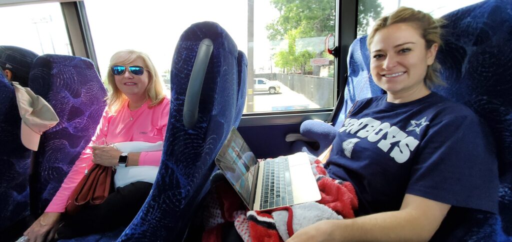 Two women sitting on a bus with laptops.