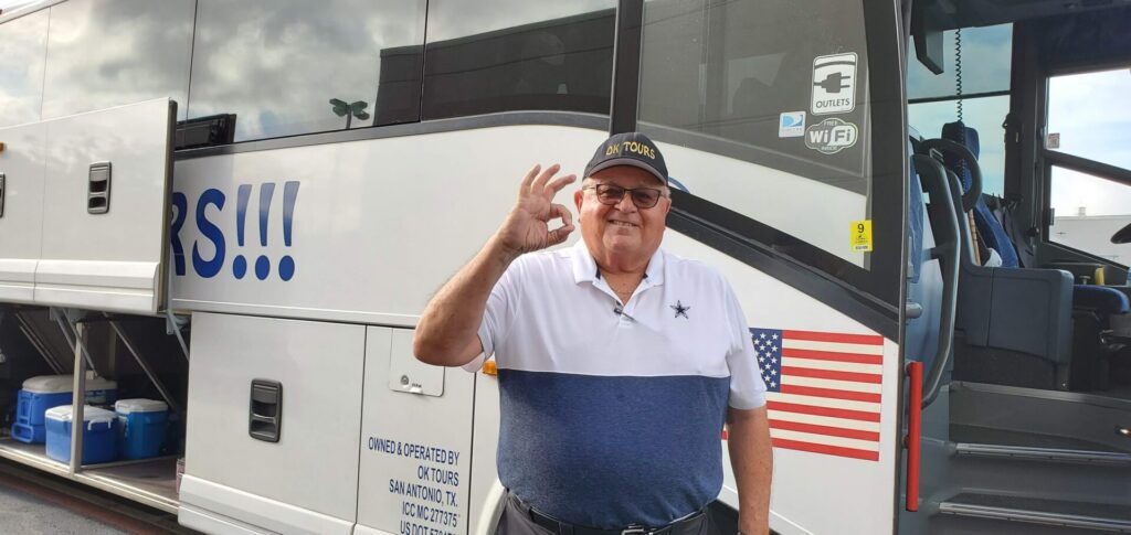 A man standing in front of a bus with an american flag.