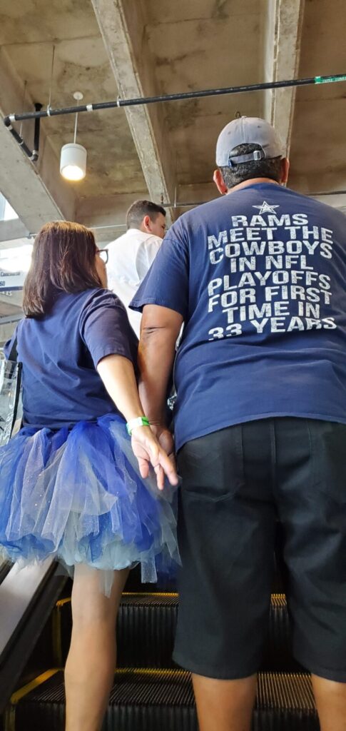 Two people standing on an escalator wearing t - shirts.