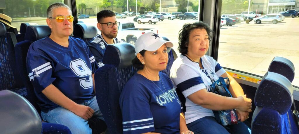 A group of people sitting on a bus with cowboys shirts.