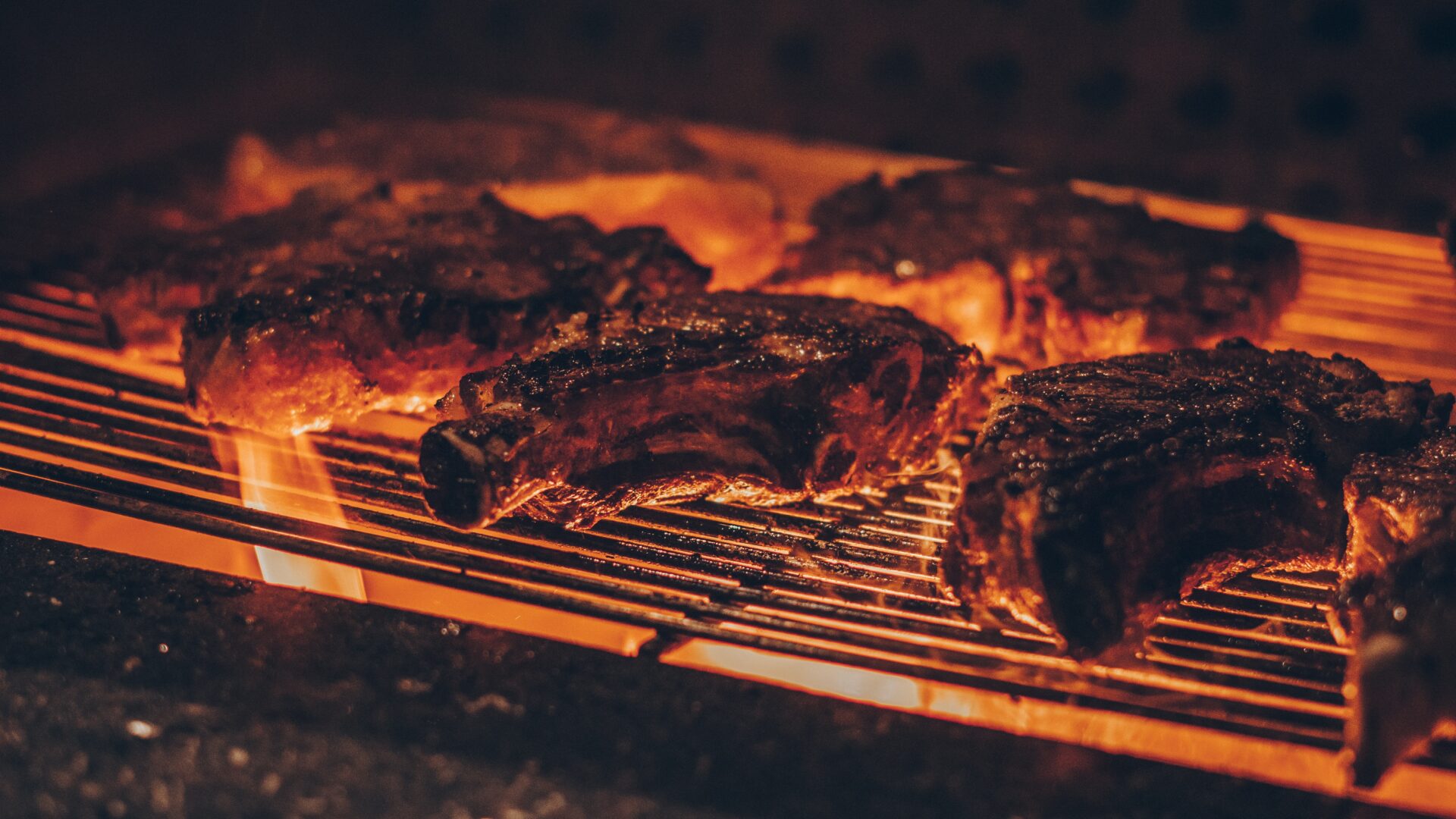 emerson-vieira-3wzps8KbdCQ-unsplash Some steaks are being cooked on a grill.