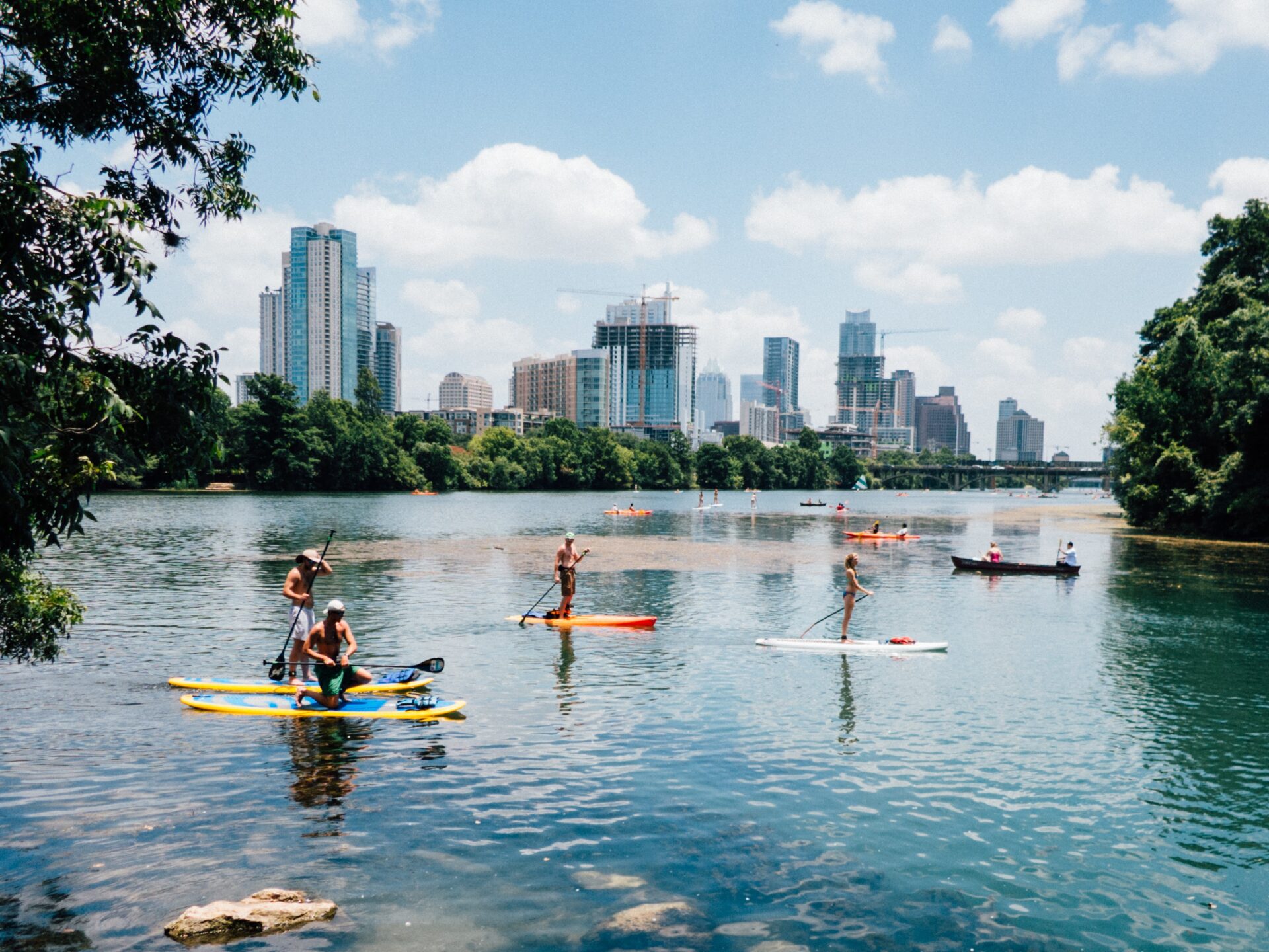 A group of people stand up paddle boarding in a river.