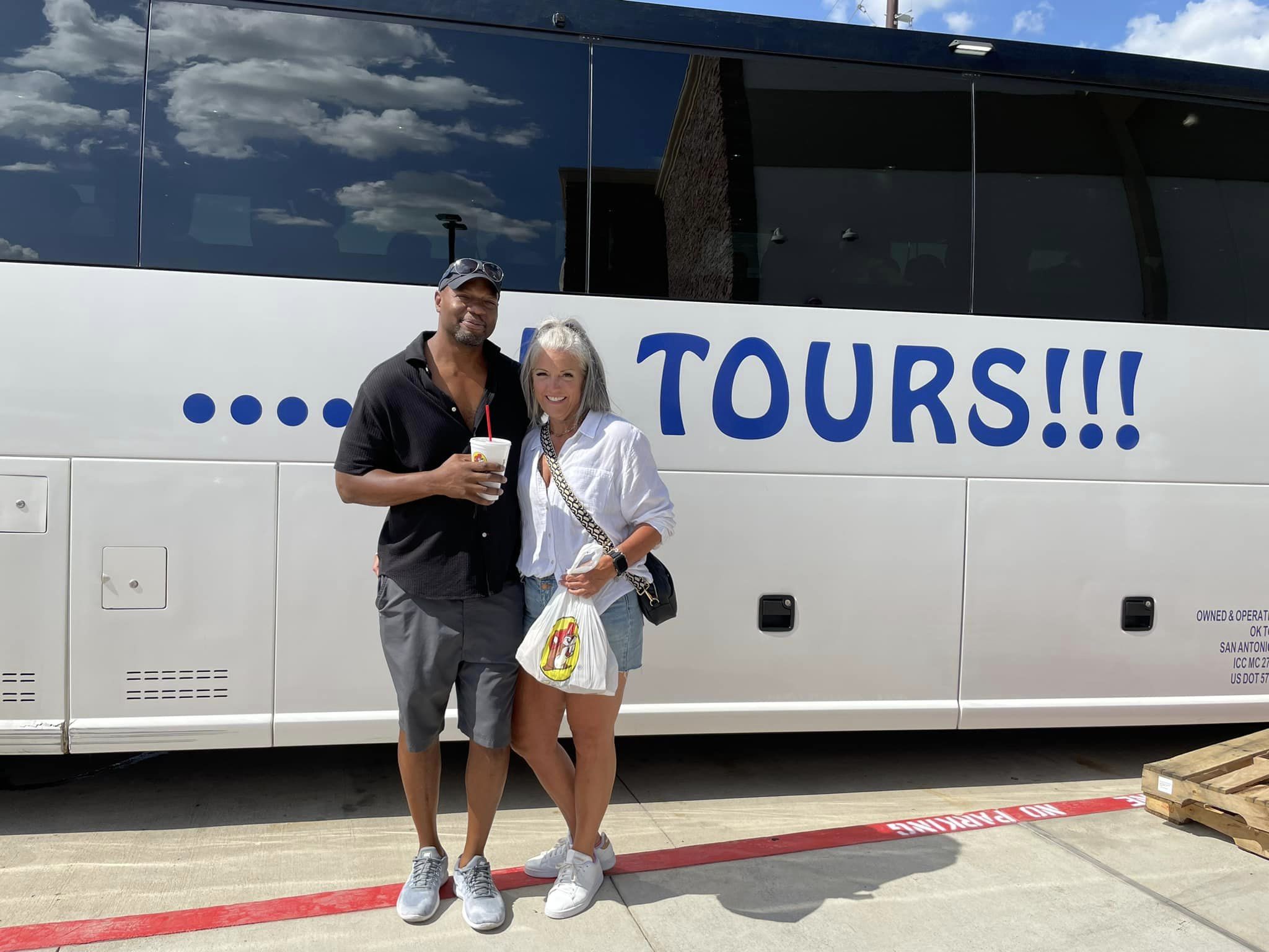 A man and woman standing in front of a tour bus.